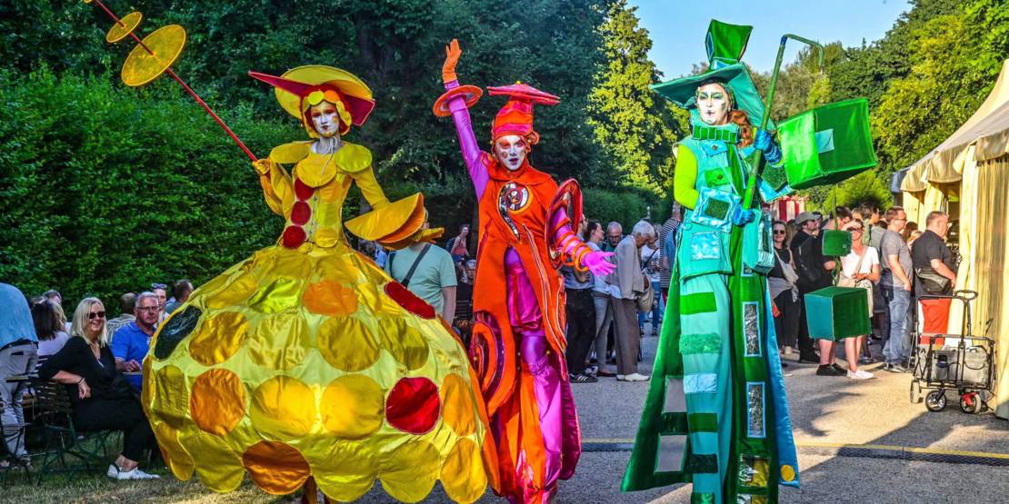Drei bunt gekleidete Stelzenläufer beim Kleinen Fest im Großen Garten.
