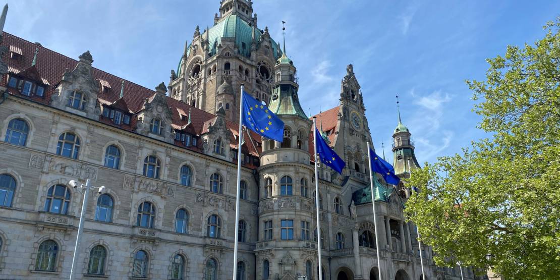 Fahnen wehen vor dem Neuen Rathaus im Wind.