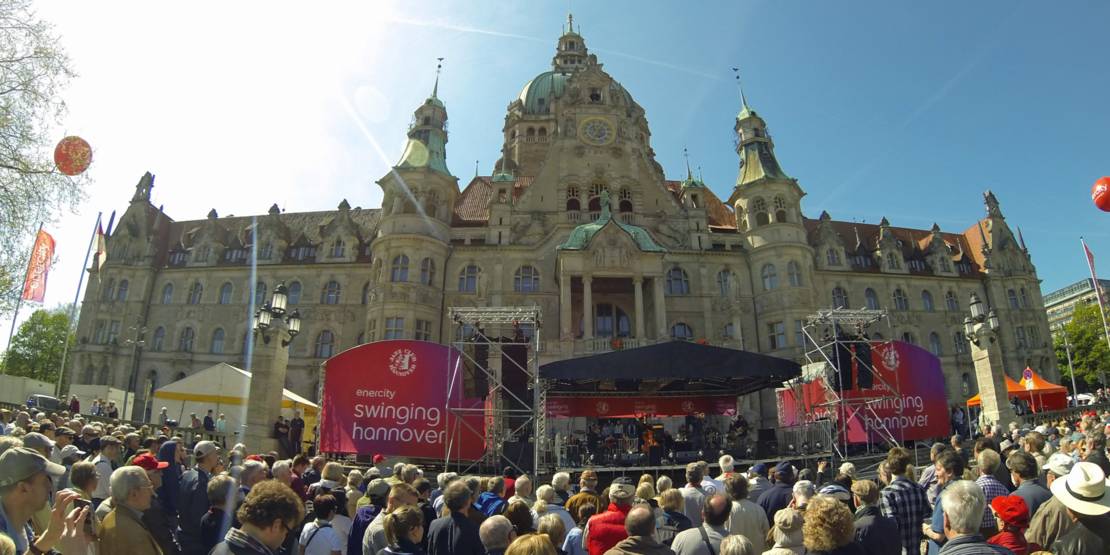 Menschen vor einer Bühne am Neuen Rathaus.