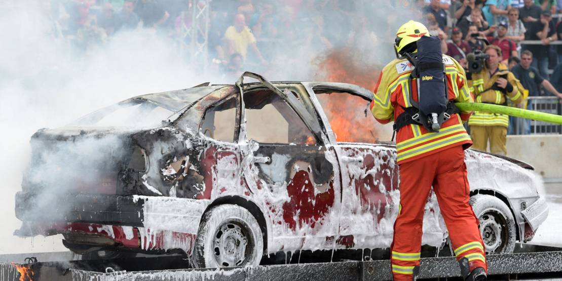 Feuerwehrmann löscht ein brennendes Auto.