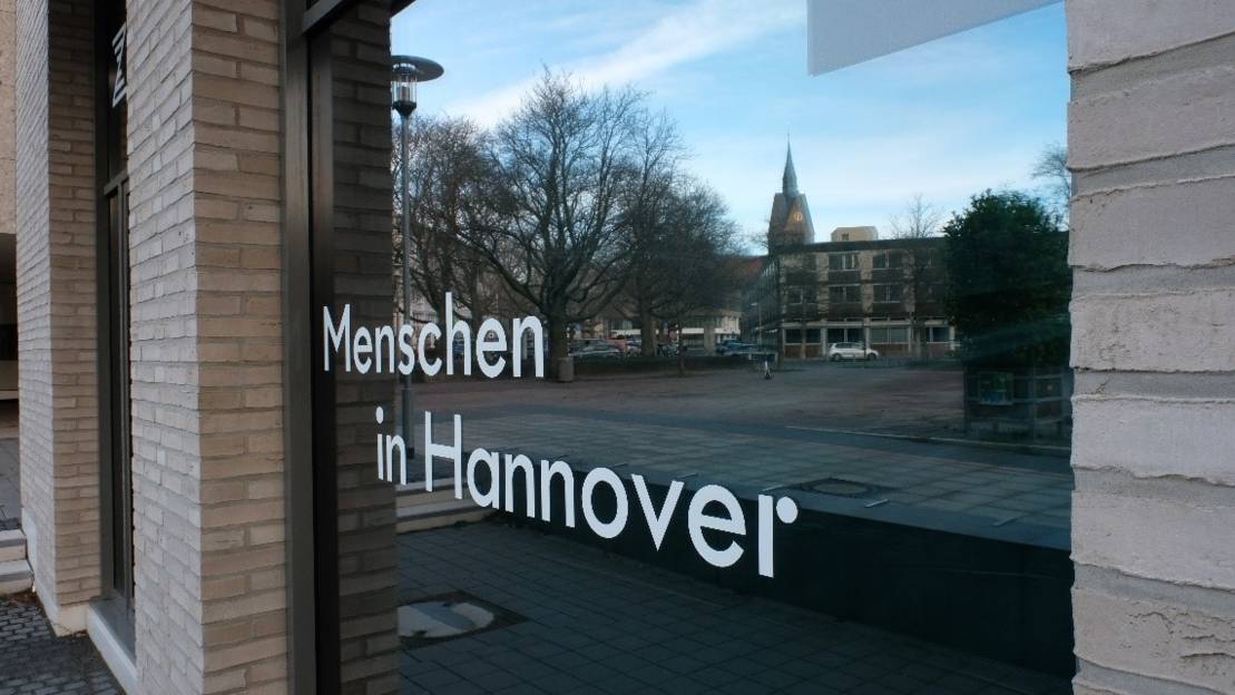 Zu sehen ist die Hausfassade des ZeitZentrum Zivilcourage in einer Nahaufnahme. Auf dem Fensterglas steht "Menschen in Hannover".