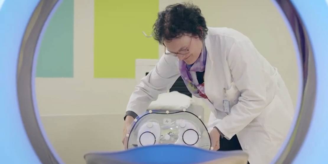 Frau in Doktorkittel an einem technischen Gerät.