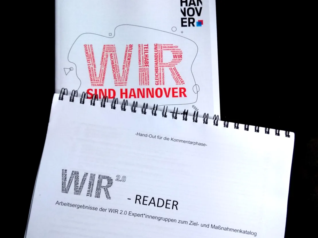 Ein Reader mit der Aufschrifft "WIR 2.0-Reader. Arbeitsergebnisse der WIR 2.0-Expert*innengruppen zum Ziel- und Ma&szlig;nahmenkatalog". Darunter sieht man den oberen Teil des Strategiepapiers mit der Aufschrift "WIR sind Hannover".