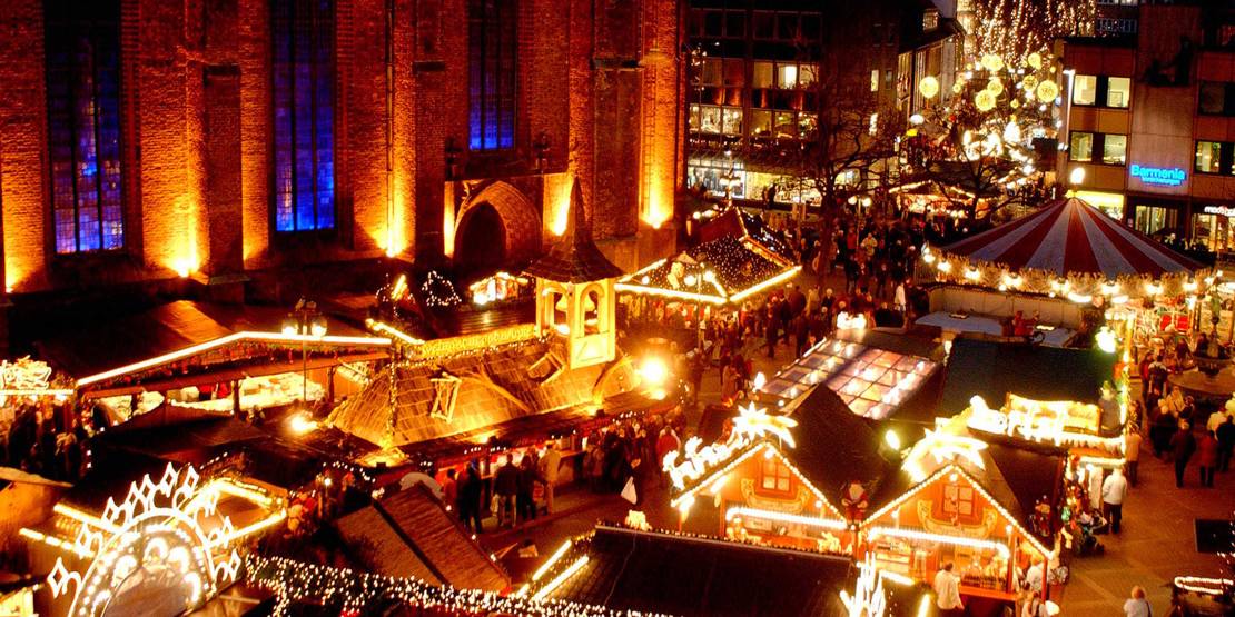 Blick von oben auf das beleuchtete Kirchenschiff der Marktkirche und die aufgebauten Weihnachtsmarktstände