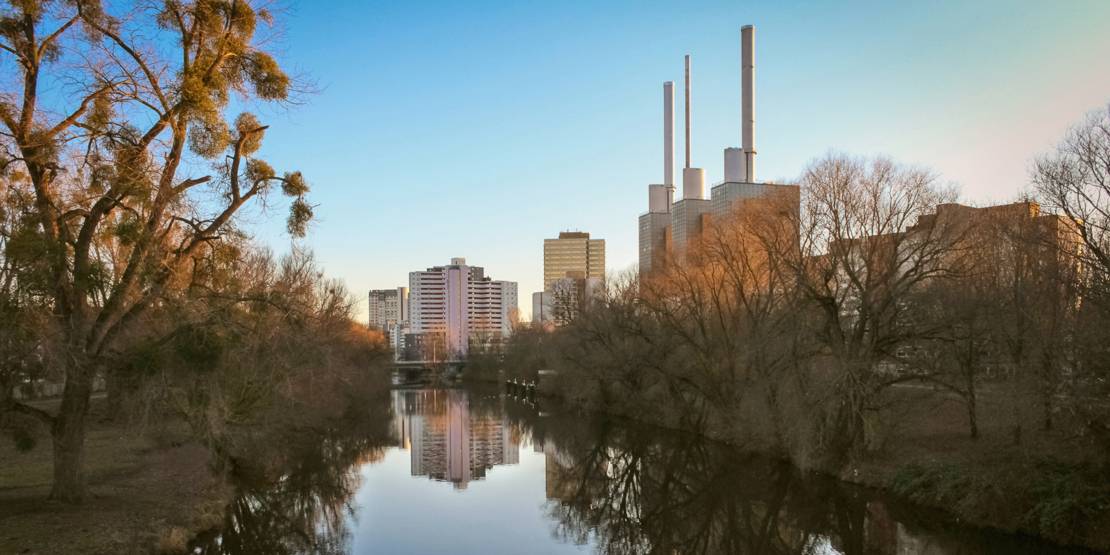 Blick auf ein Fluss mit kahlen Bäumen am Ufer, im Hintergrund das Ihmezentrum.