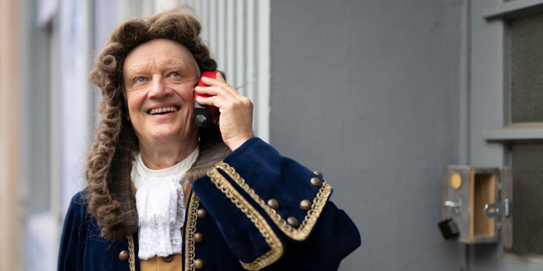 Eine Schauspieler in Verkleidung hält ein Handy an sein Ohr.