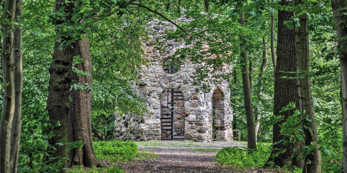 Drei Meter hoher Turmsockel von Bäumen umgeben.