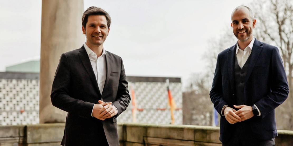 Zwei Herren im Anzug auf dem Balkon des Neuen Rathauses in Hannover.