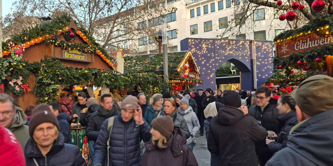 Das blaue Eingangstor des Weihnachtsmarkts Hannover sowie Stände und Menschen davor