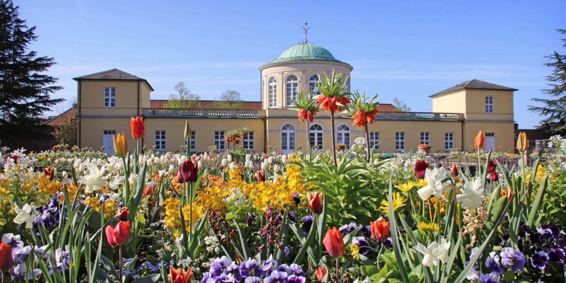 Historisches Gebäude mit Sommerblumenbeeten im Vordergrund