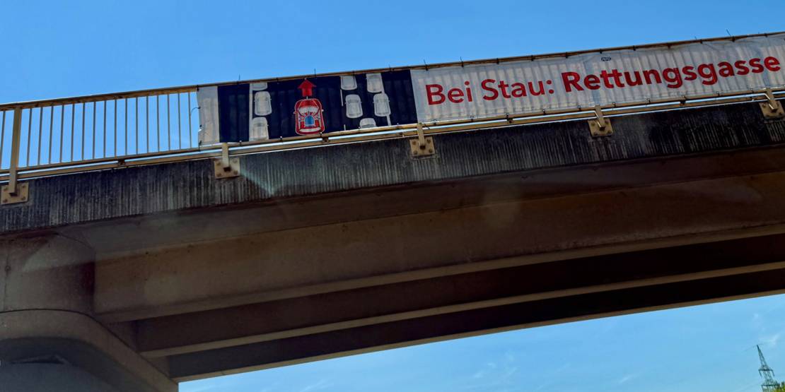 Eine Brücke mit einem Schild, dass bei Stau eine Rettungsgasse gebildet werden muss