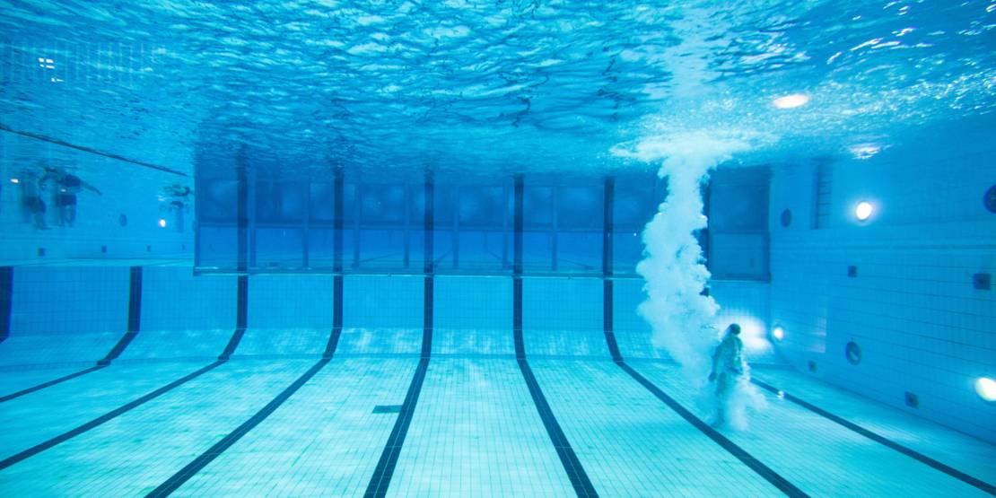Unterwasseraufnahme einer Person, die ins Schwimmbecken gesprungen ist