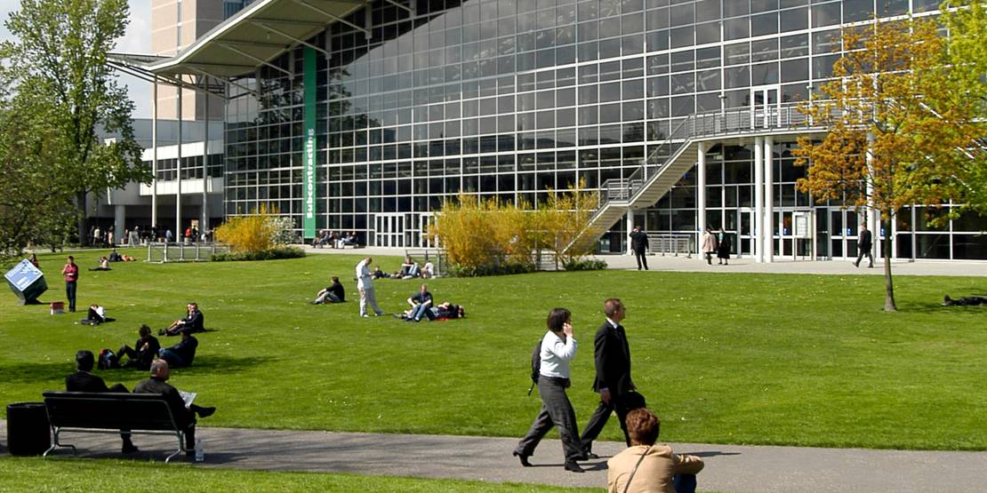 Halle auf dem Messegelände Hannover. Rund um das Gebäude sind Besucherinnen und Besucher zu sehen.
