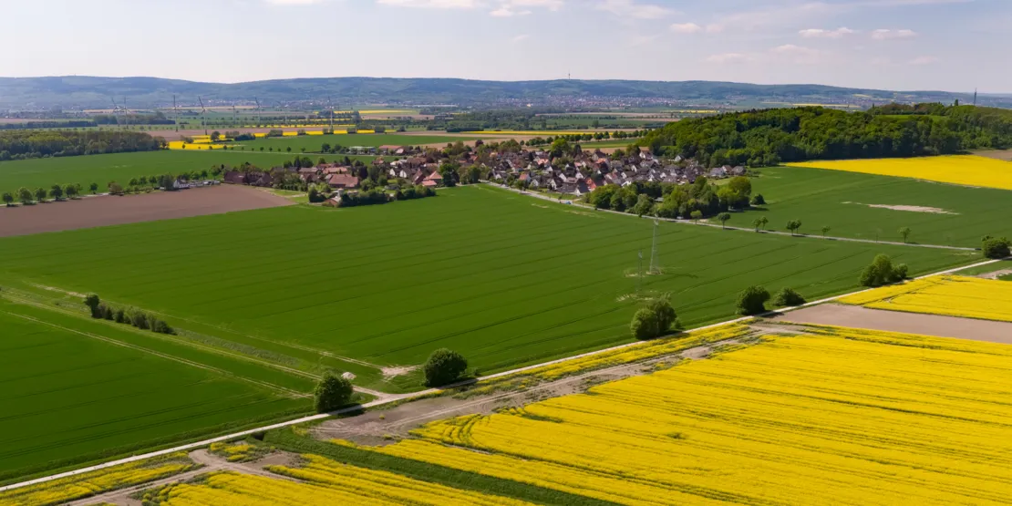 Luftbild der Ortschaft Göxe, im Hintergrund Windkraftanlagen und der Deister