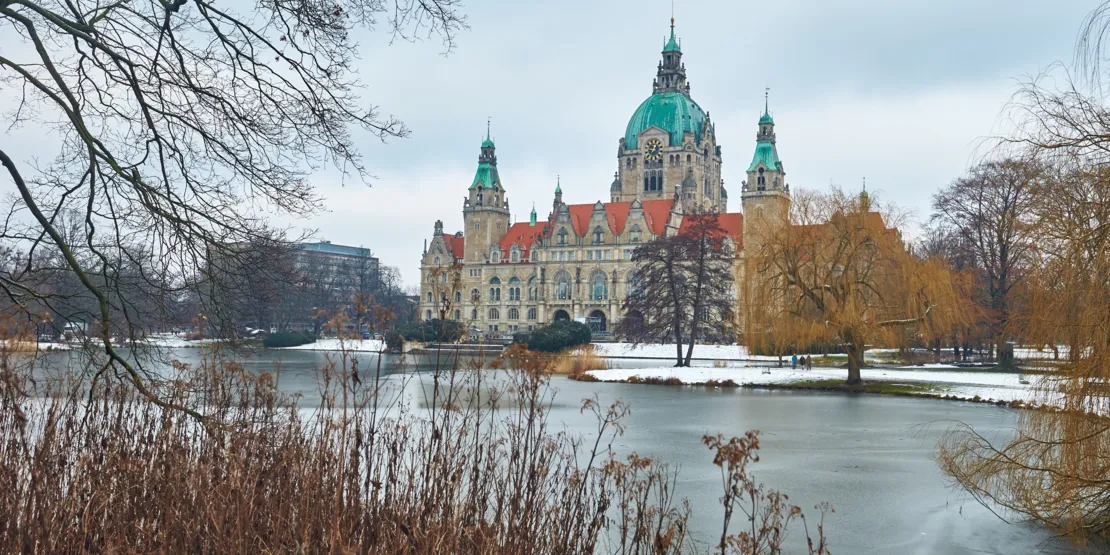 Historisches Gebäude hinter einem Teich in einem winterlichen Park.