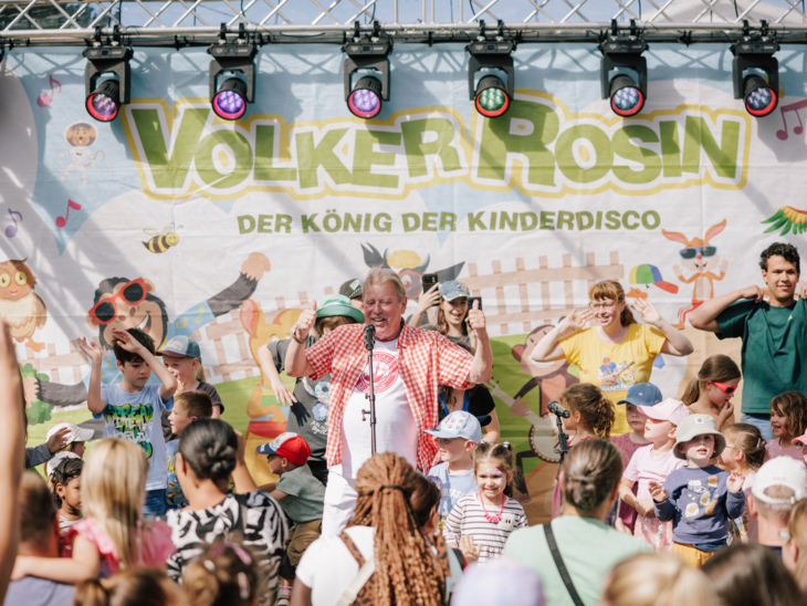 Ein Mann auf einer Bühne, davor viele Kinder.
