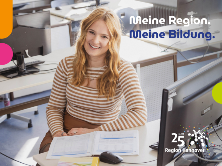 Eine junge Frau sitzt in der Berufsschule am Computer mit ihren Schulbüchern.