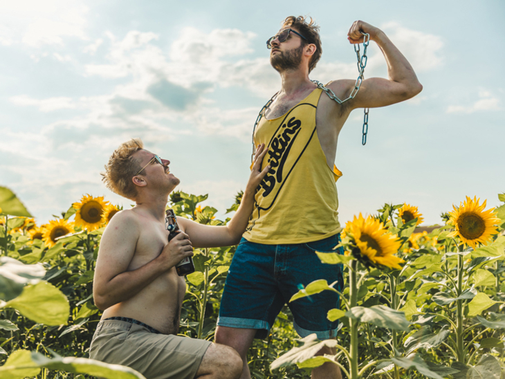 Ein Mann kniet vor einem anderen Mann in einem Sonnenblumenfeld
