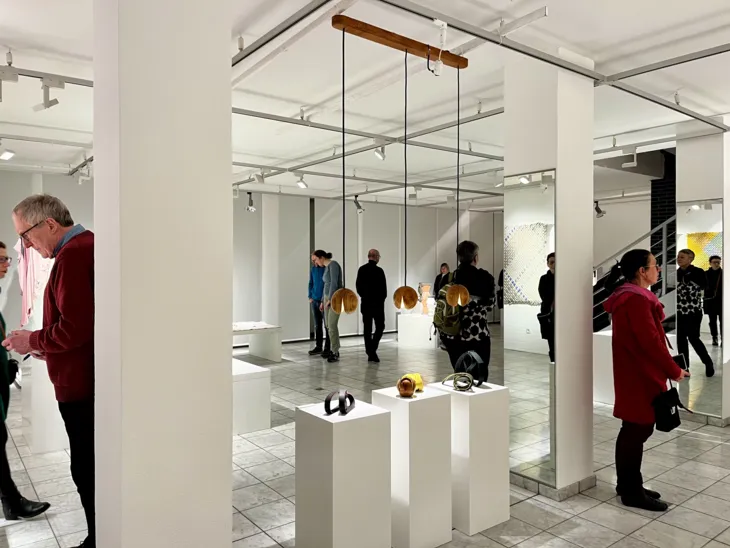 Personen schauen sich auf Sockeln präsentierte Kunstwerke an.
