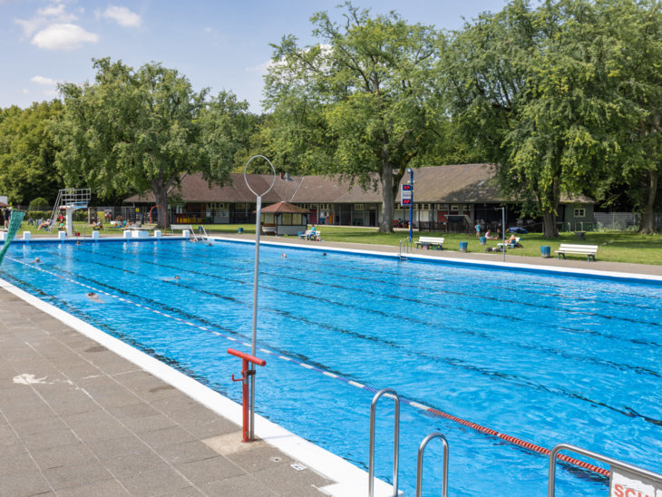 Schwimmbecken eines Freibades, im Hintergrund Gebäude