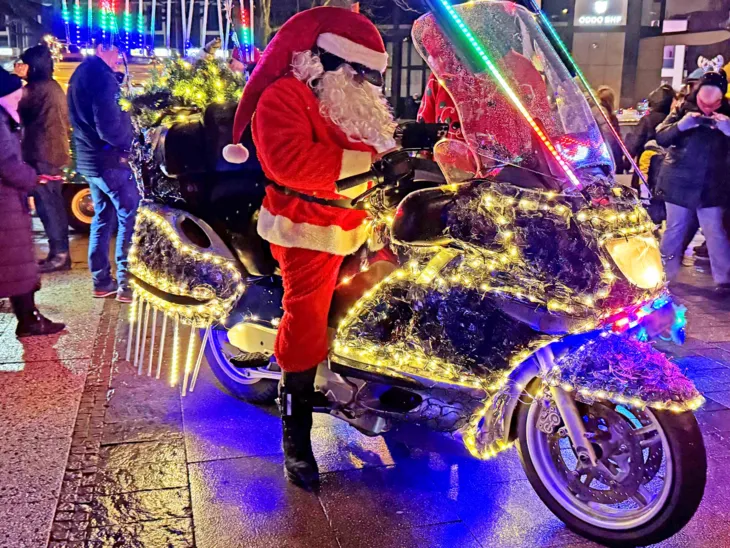 Motorrad mit Leuchtketten behangen mit einem als Weihnachtsmann verkleideten Fahrer.