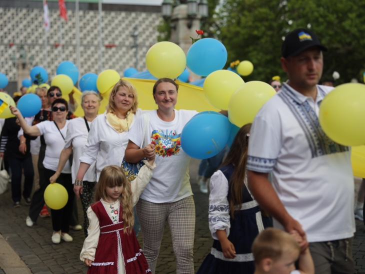 Menschen bei einem Ausmarsch mit blau-gelben Luftballons.