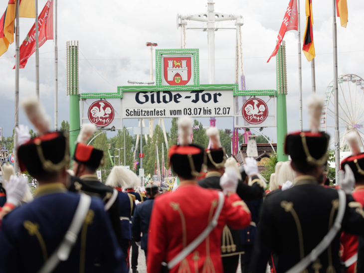 Menschen bei einem Umzug vor einem Tor.