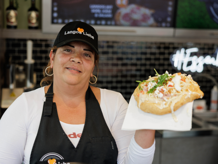 Eine Frau, die ein Langos in der Hand hat.