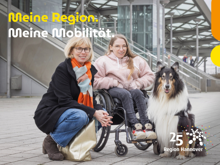 Eine Frau mit Rollstuhl und einem Assistenzhund vor einer Stadtbahnhaltestelle.
