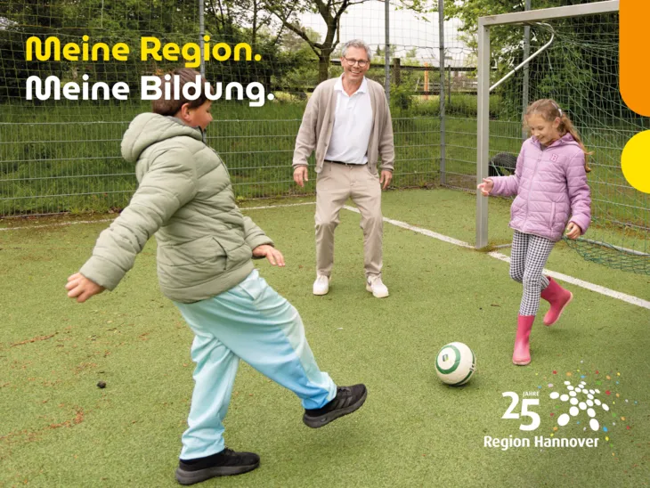 Ein Förderschullehrer spielt mit Kindern draußen Fußball.