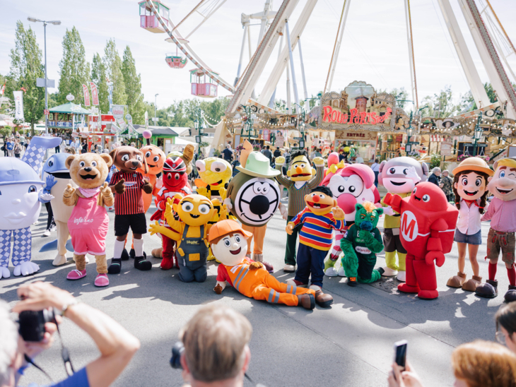 Zahlreiche Maskottchen auf einem Festplatz.