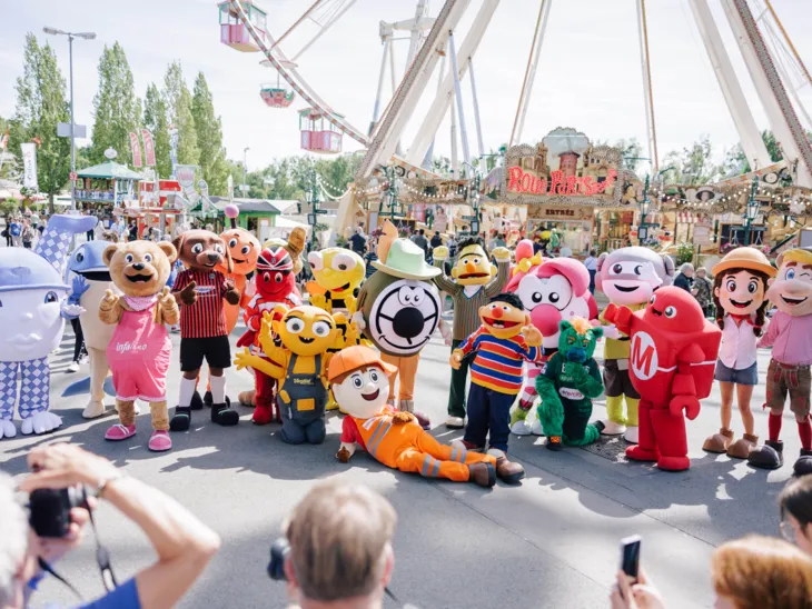 Zahlreiche Maskottchen auf einem Festplatz.