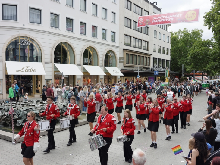 Schützen und Schützinnen auf einer Straße. Drumherum viele Menschen.