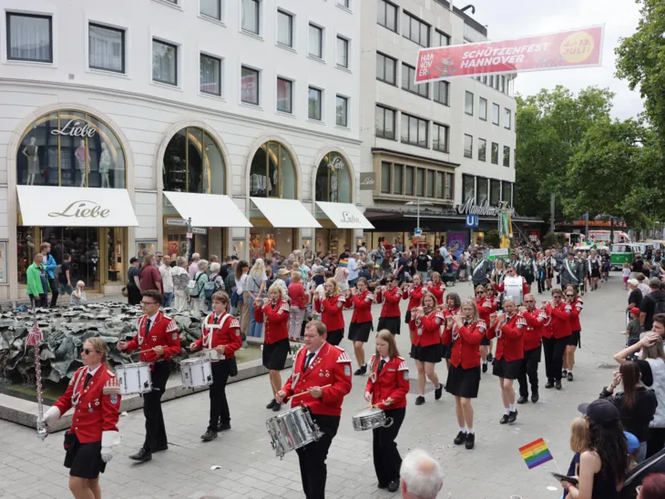 Schützen und Schützinnen auf einer Straße. Drumherum viele Menschen.