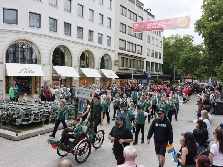 Schützen und Schützinnen auf einer Straße. Drumherum viele Menschen.