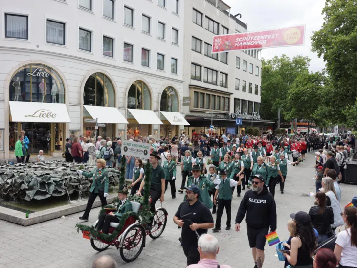 Schützen und Schützinnen auf einer Straße. Drumherum viele Menschen.