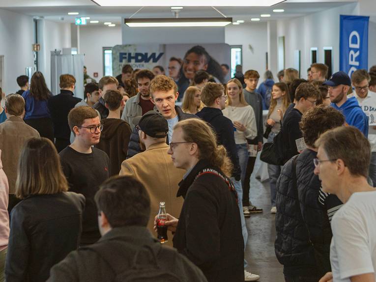 Viele junge Menschen stehen im Flur und unterhalten sich