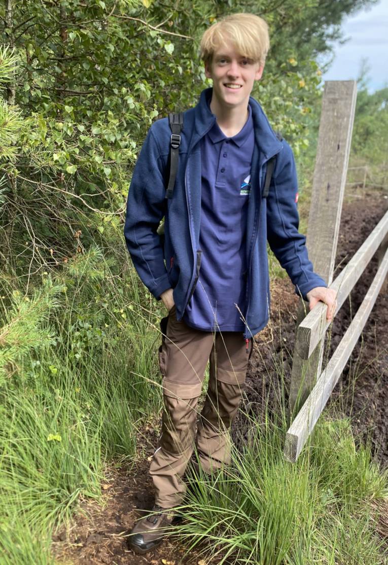 Jemand steht an einem Barfu&szlig;pfad im Moor.