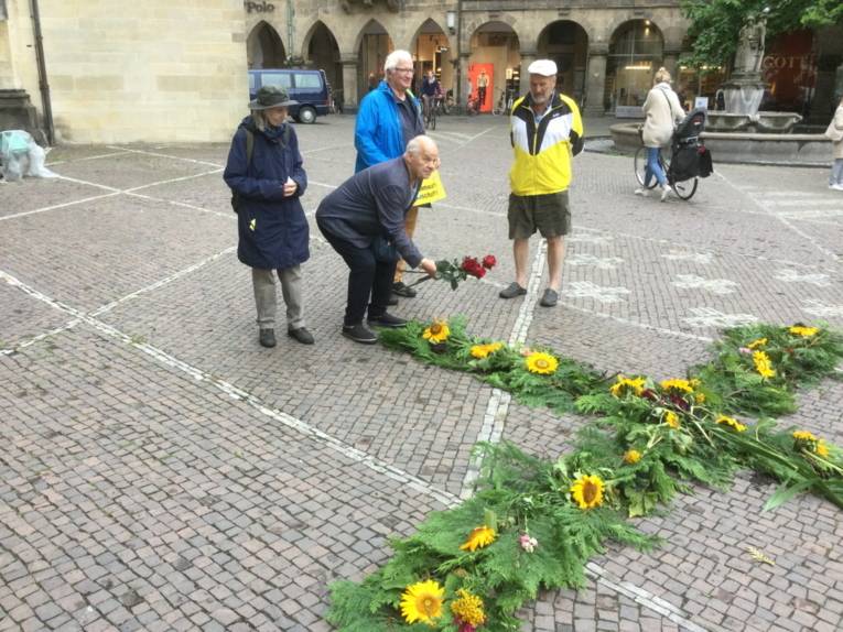 Frauen und Männer legen Blumen in Münster ab.