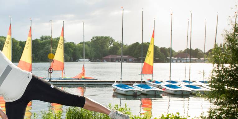 Eine Person bewegt sich sportlich an einem See.