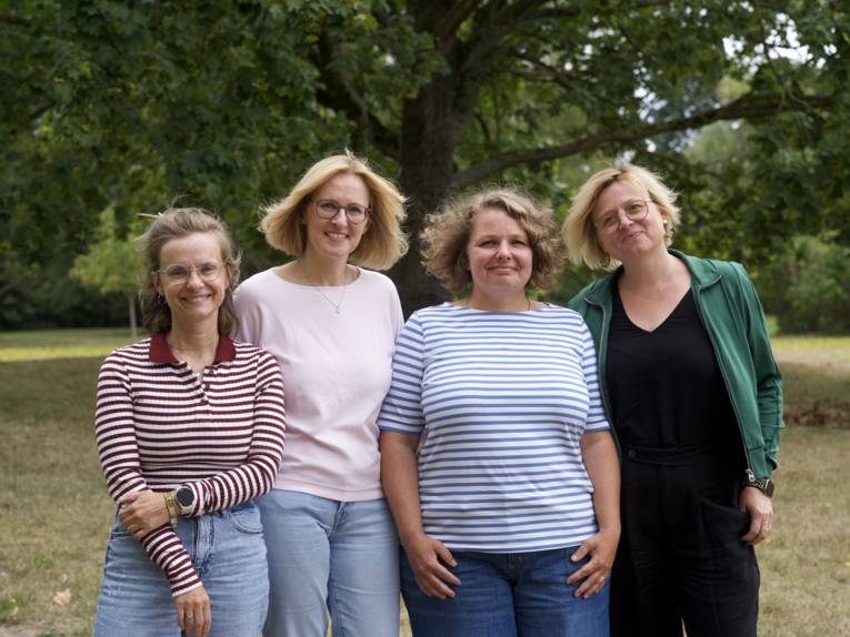 Vier Frauen stehen draußen nebeneinander