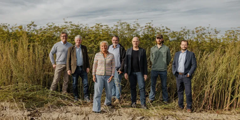 Gruppen von Personen auf einem Acker vor einem Insektenwall stehend