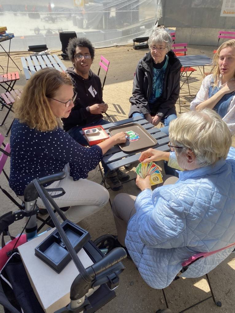 Menschen verschiedenen Alters spielen Kartenspiele auf dem Fiedelerplatz.