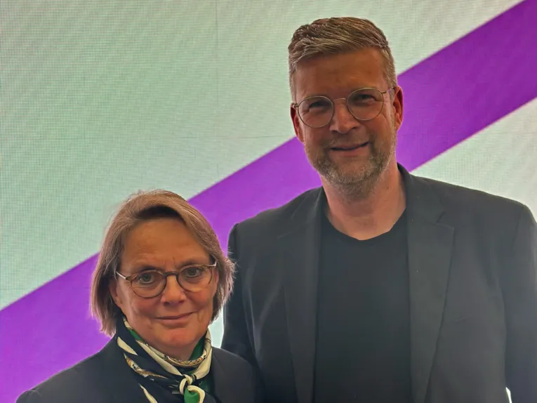 Eine Frau und ein Mann stehen vor einer Leuchttafel.