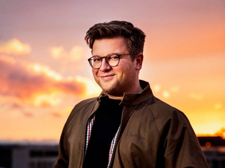 Ein Mann mit einem Sonnenuntergang im Hintergrund.