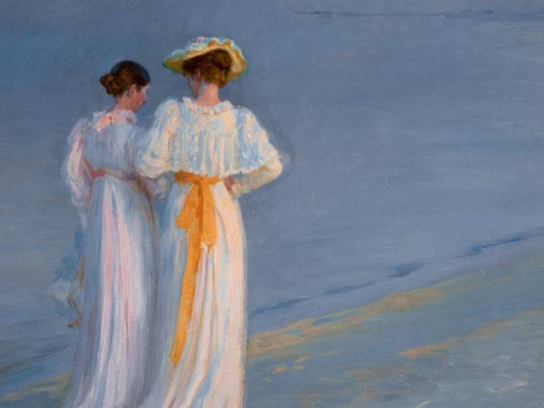 Zu sehen ist eine impressionistische Malerei: Zwei Frauen in altmodischen Kleidern schlendern bei untergehender Sonne am Strand entlang.