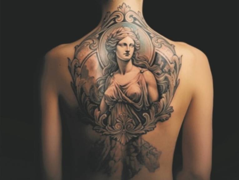 Neuzeitliches Tattoo auf dem gesamten nackten Rücken einer Frau mit dem Motiv einer antiken Göttin. Der Hintergrund ist schwarz.