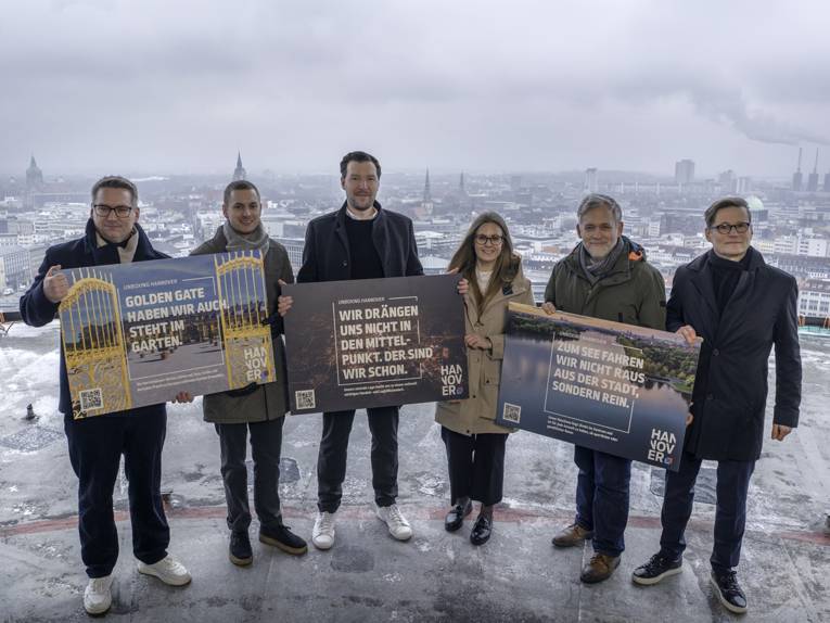 Fünf Männer und eine Frau halten Plakate in den Händen.