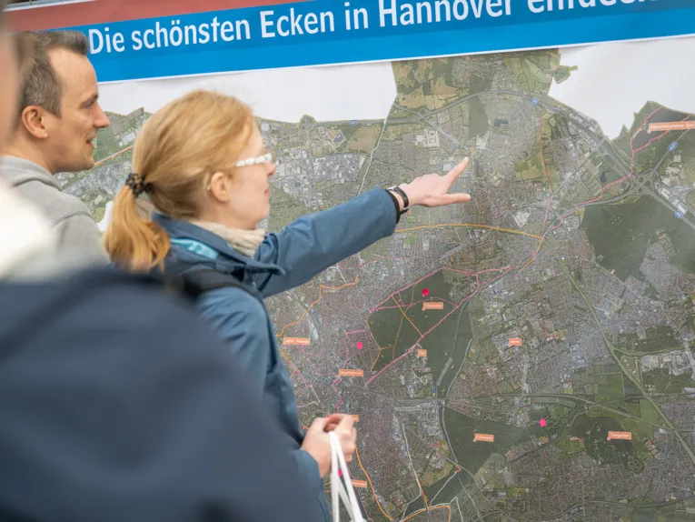 Eine Frau zeigt auf eine gro&szlig;e Karte von Hannover.
