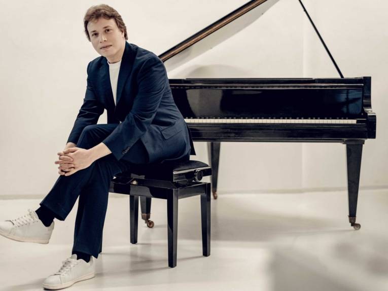 Ein Mann sitzt vor einem Konzertflügel